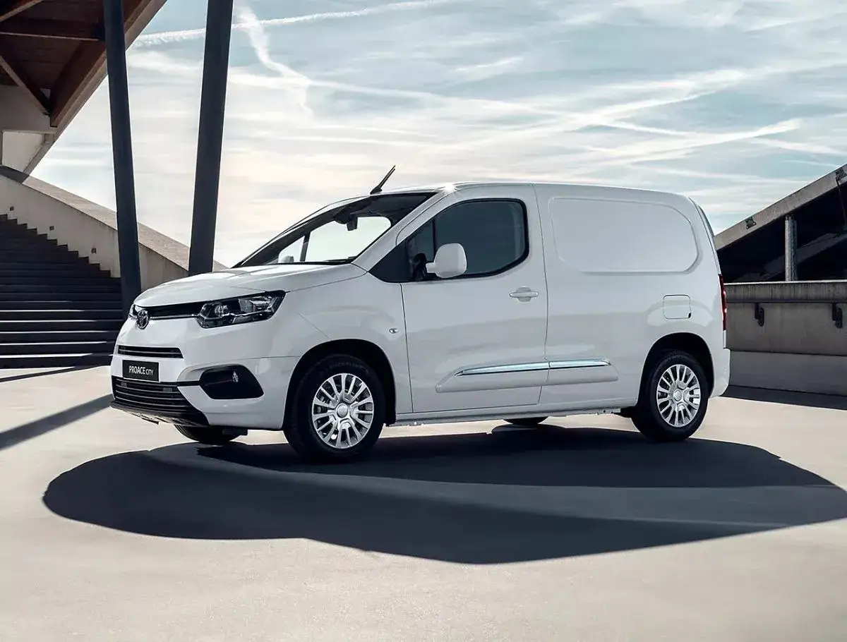Biały van Toyota Proace City, jeden z wielu wszechstronnych **toyota modele**, zaparkowany na tle nowoczesnej architektury.