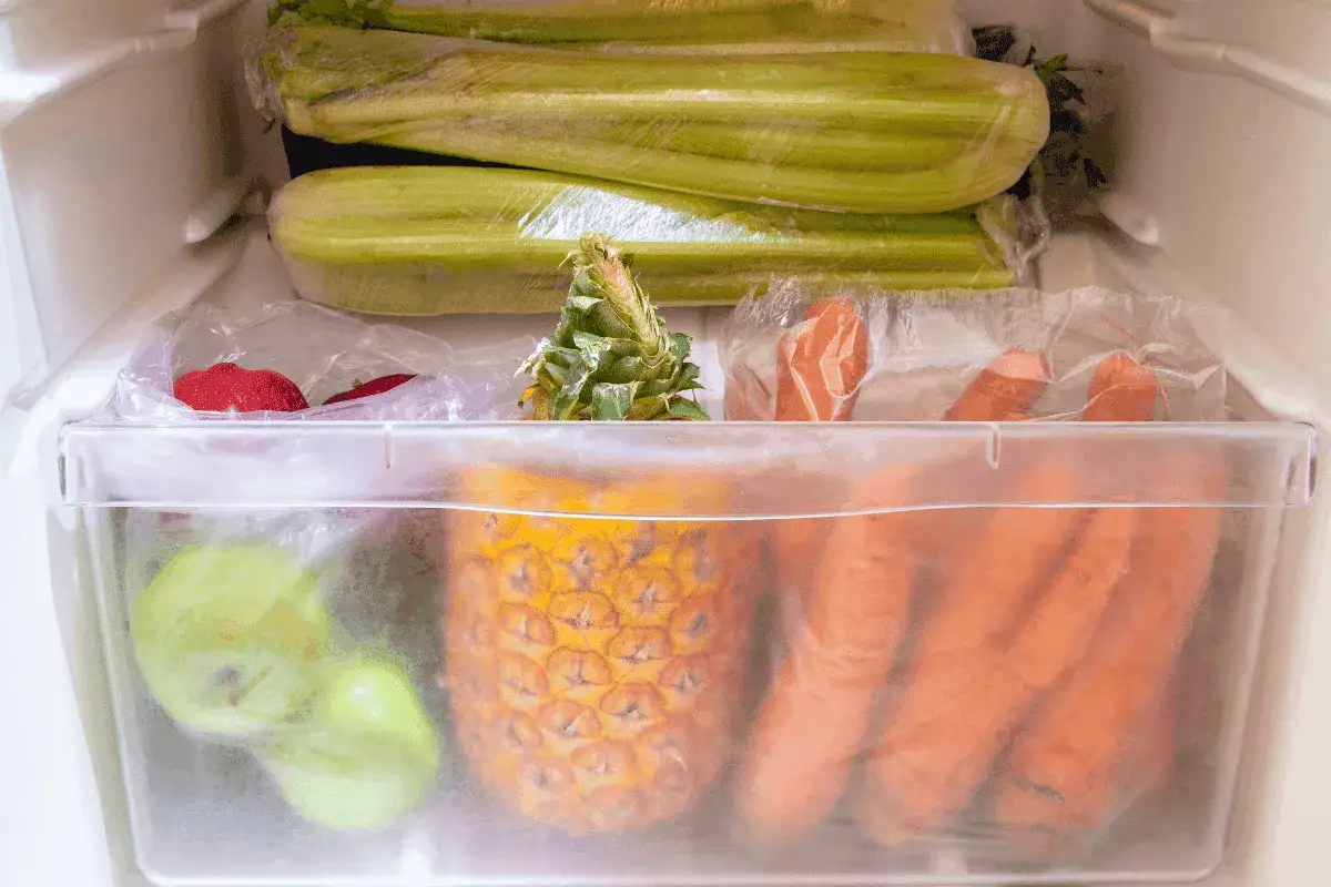Karotten richtig lagern: Frische Karotten, Sellerie, Ananas und Äpfel im Kühlschrank.