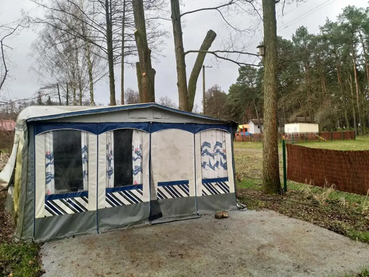 Przygotowane miejsce pod przyczepę kempingową nad jeziorem, otoczone drzewami.