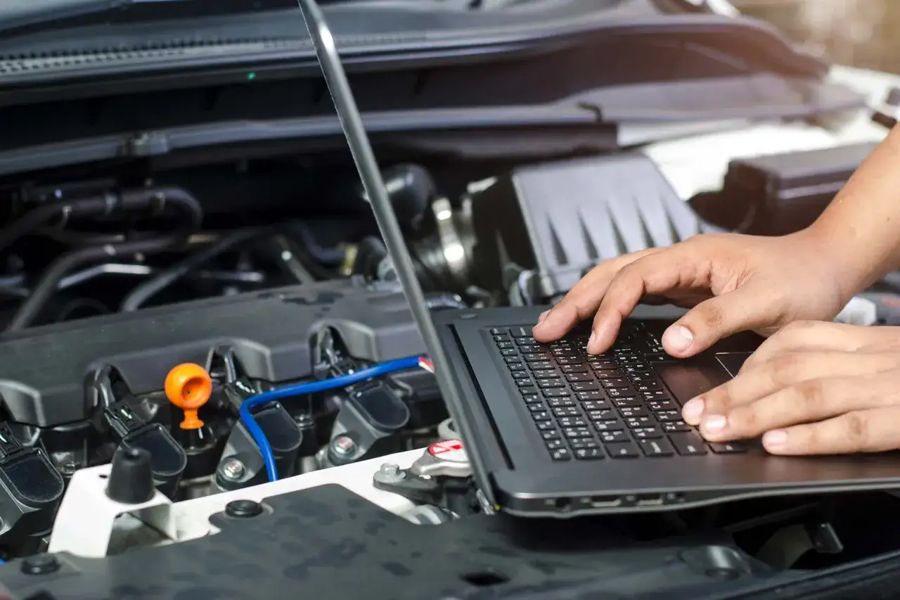 Mechanik diagnozuje problem z silnikiem, który nie ma mocy i szarpie, używając laptopa do analizy danych.
