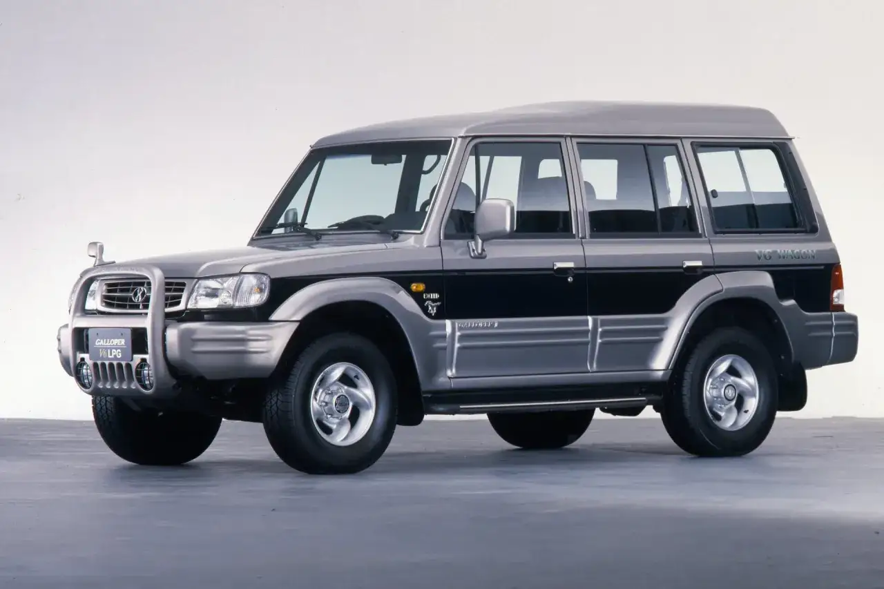 Srebrny Hyundai Galloper V6 LPG, terenowy SUV z lat 90. z czarnymi pasami na drzwiach.