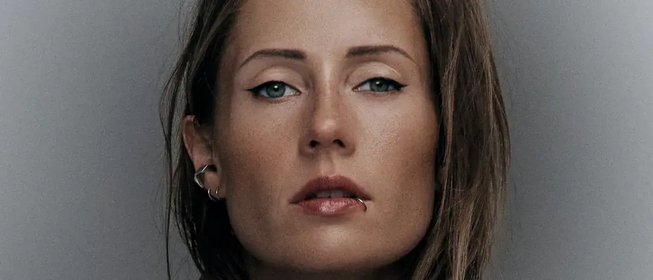 Primo piano di Charlotte de Witte, DJ e produttrice, con un trucco deciso e piercing. Immagine promozionale per i suoi eventi.