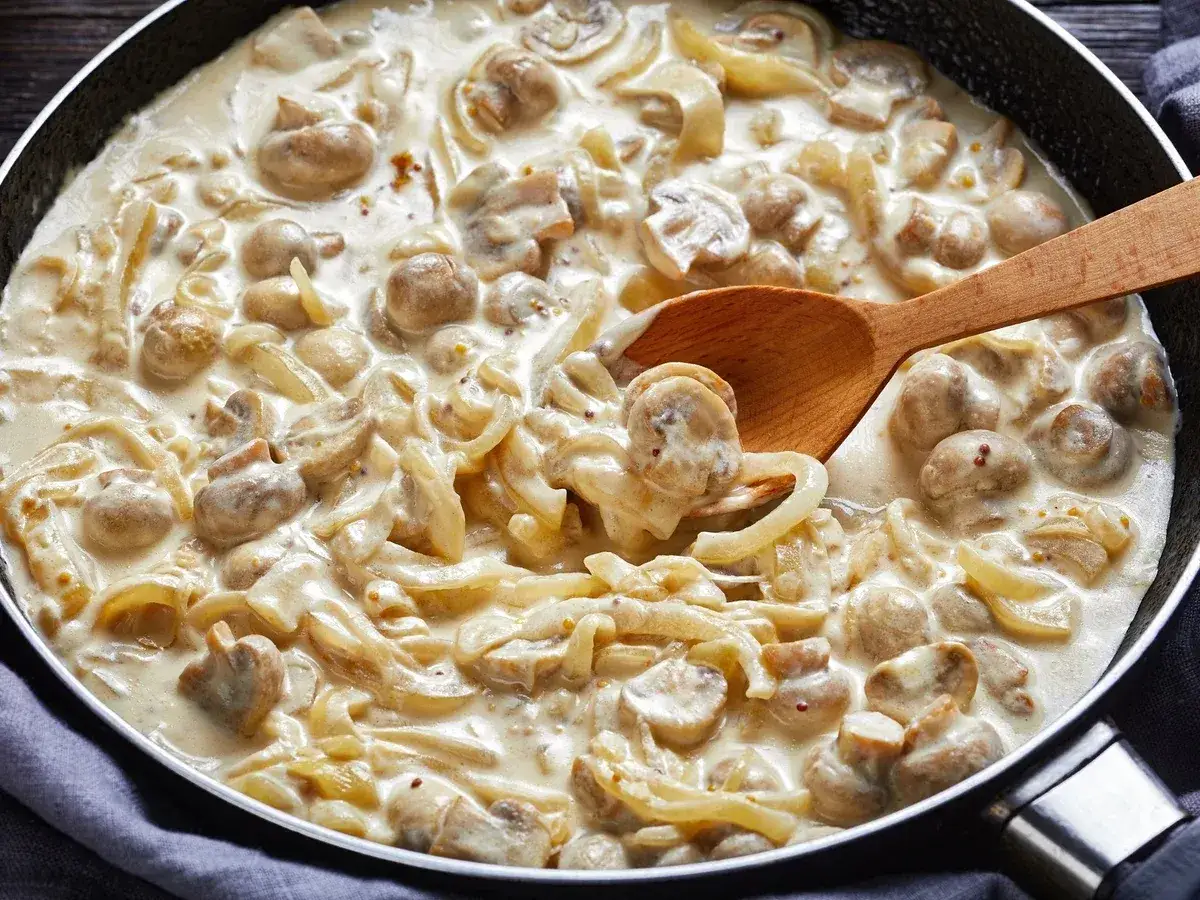 Cremiges Putengeschnetzeltes mit Pilzen und Zwiebeln in einer Pfanne, perfekt für ein einfaches Rezept.