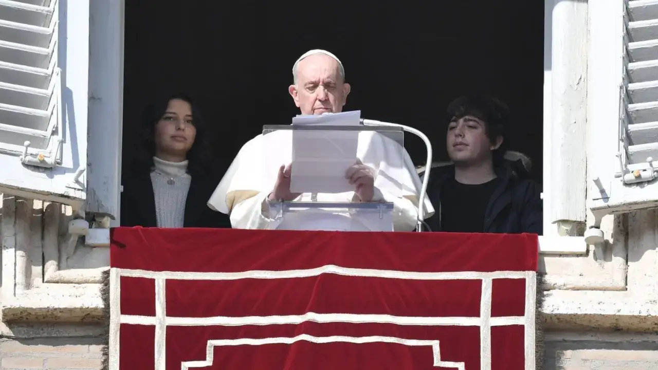 Głowa kościoła, papież Franciszek, przemawia z okna, otoczony młodymi ludźmi.