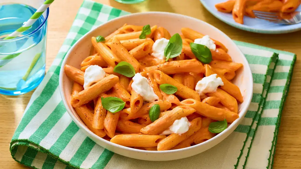 Penne w kremowym sosie pomidorowym z kawałkami mozzarelli i listkami bazylii. Idealne danie, gdy masz ochotę na pyszny makaron z mozzarellą.