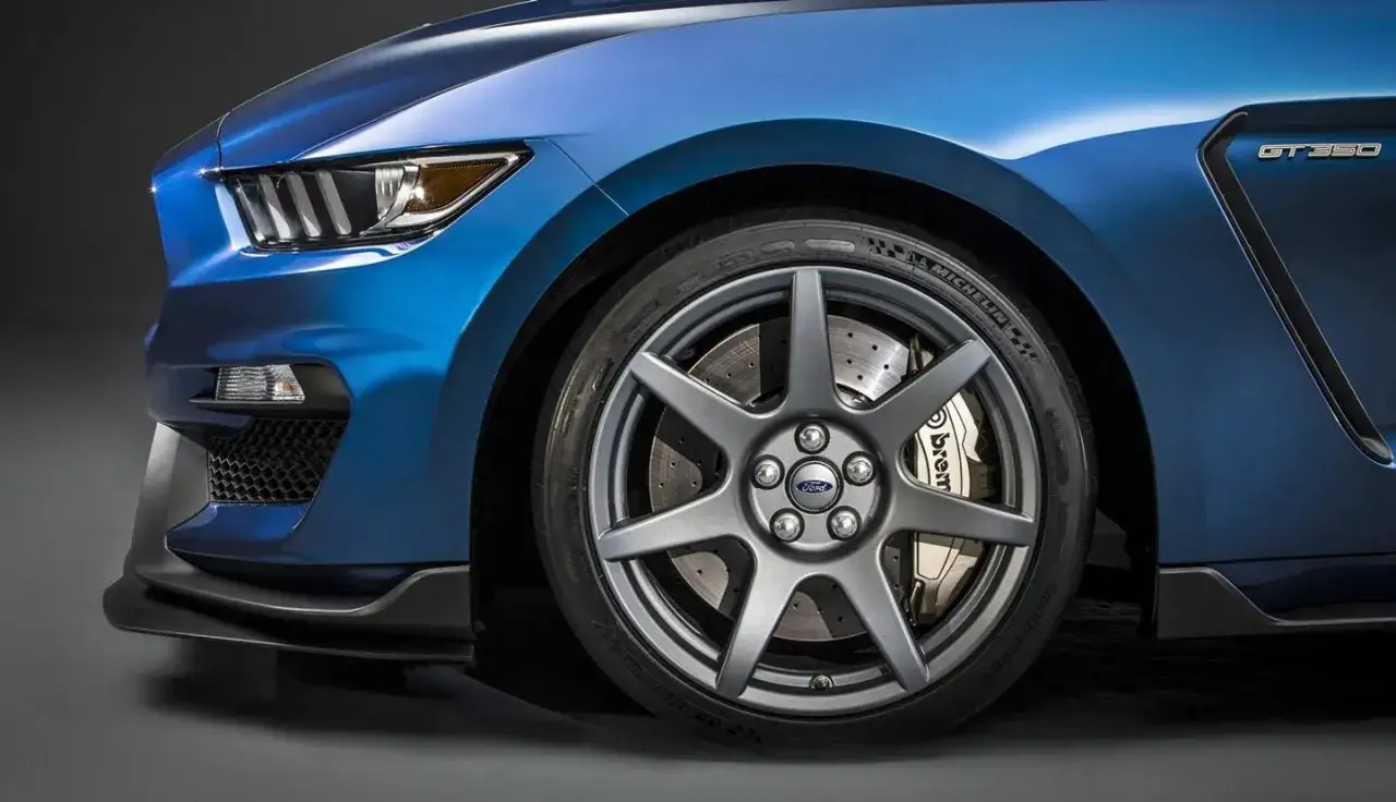 Rueda de un Ford Mustang GT350 azul con discos perforados y pinzas Brembo doradas.