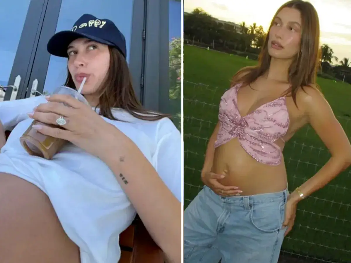 Hailey Bieber w ciąży, w czapce z daszkiem i białej koszulce, pije napój. Obok, w różowym topie i jeansach, czule trzyma brzuszek.
