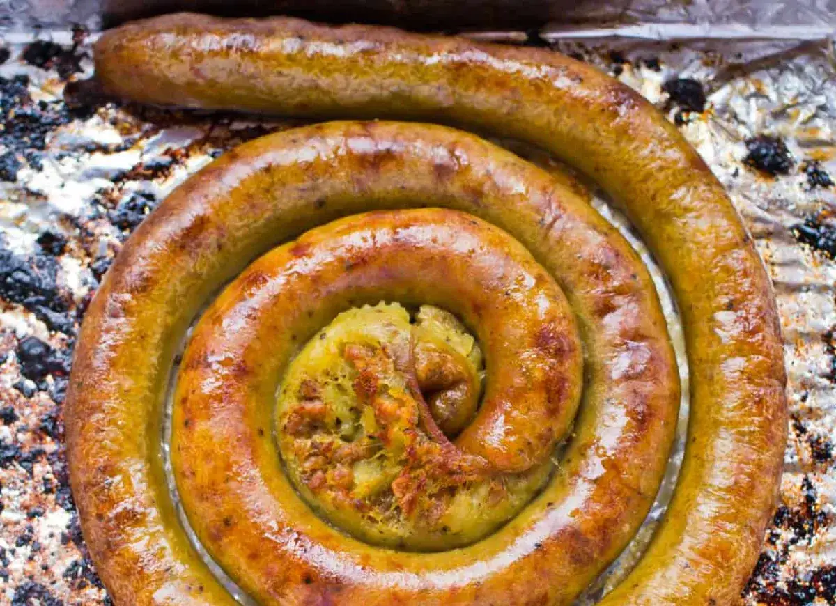 Złocista kiszka ziemniaczana, upieczona na chrupko, zwinięta w spiralę na folii aluminiowej. W środku widać apetyczny farsz.