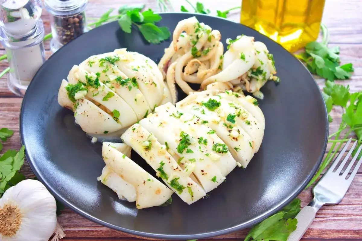 Sepia al horno, cortada y aderezada con ajo y perejil fresco, lista para disfrutar.