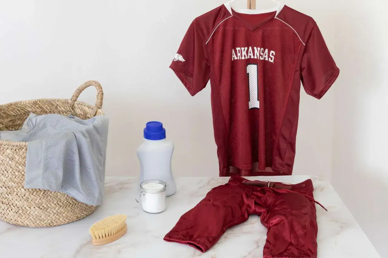 Comment laver un maillot de foot floqu&eacute; : une tenue de sport, lessive, brosse et panier &agrave; linge sont pr&ecirc;ts pour le nettoyage.