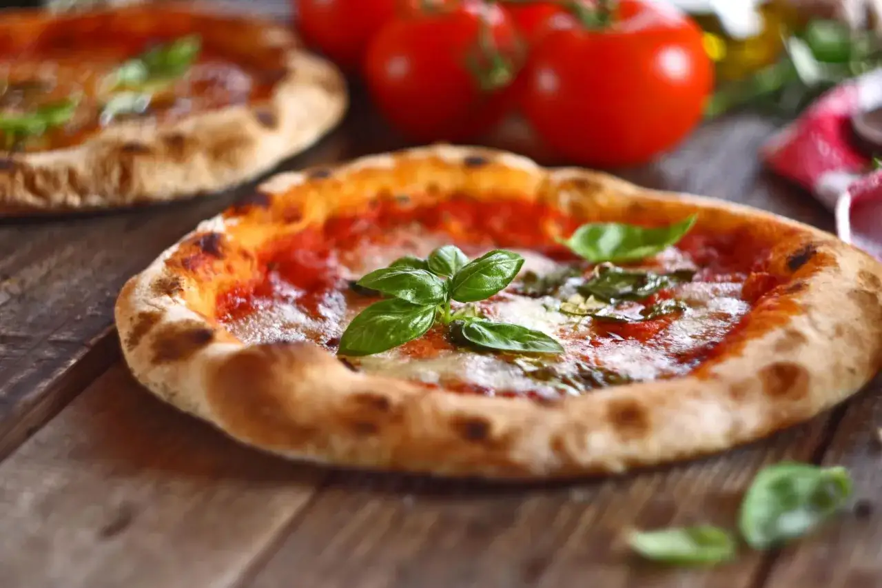 Dwie pyszne pizze na drewnianym stole. Czy pizza to fast food? Ta wygląda na dzieło sztuki!
