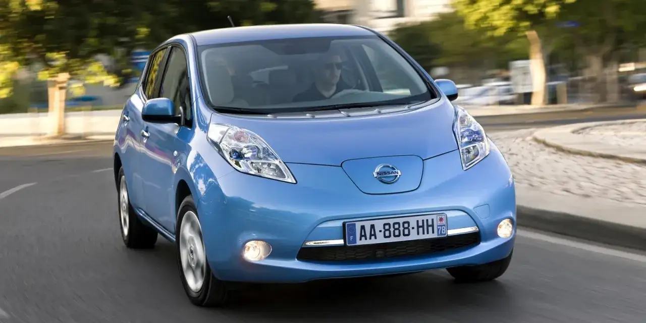 Un coche azul Nissan Leaf, uno de los coches m&aacute;s fiables de segunda mano, circula por una carretera.