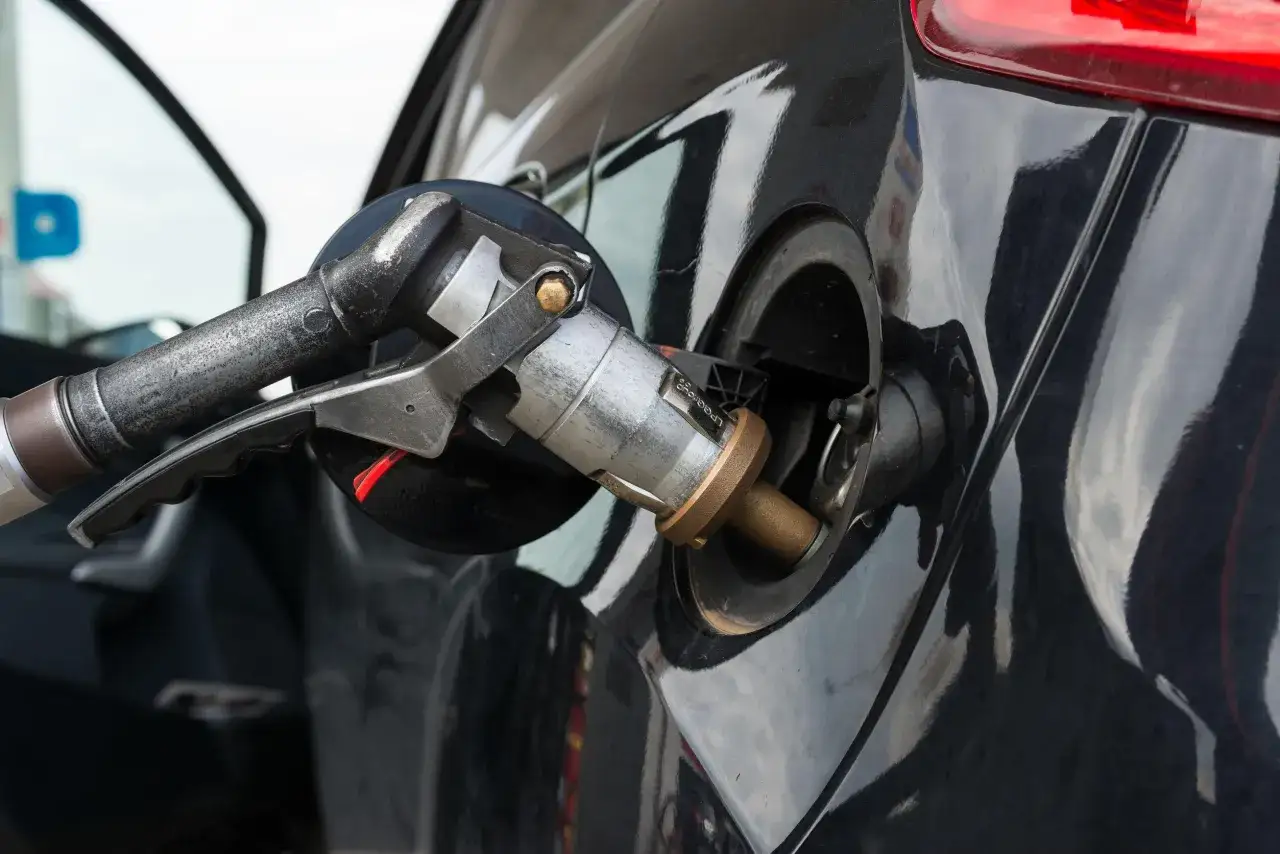 Ugello di rifornimento GPL inserito nel serbatoio di un'auto nera. Se la bombola gpl è scaduta, posso circolare a benzina?