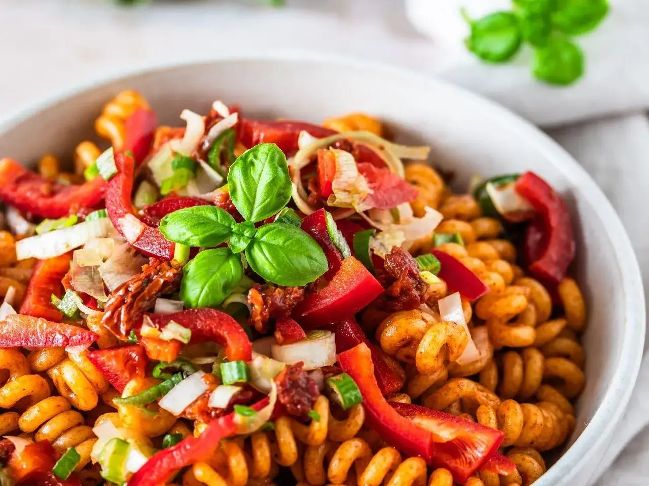 Kolorowa sałatka z makaronem fusilli, papryką, suszonymi pomidorami i bazylią. Idealna na letni obiad.