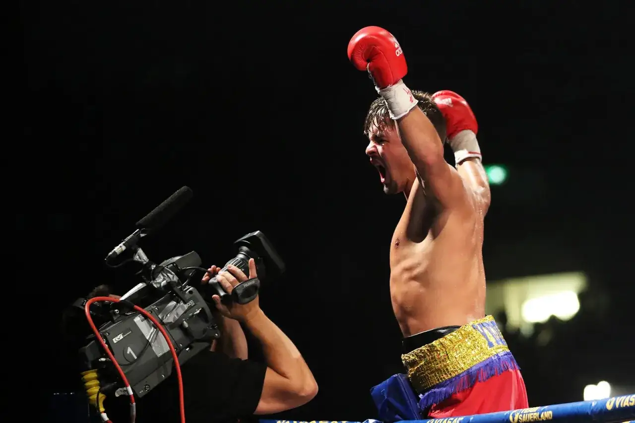 Boxaren Anthony Yigit firar en seger med uppstr&auml;ckta armar, f&aring;ngad av en kameraman.