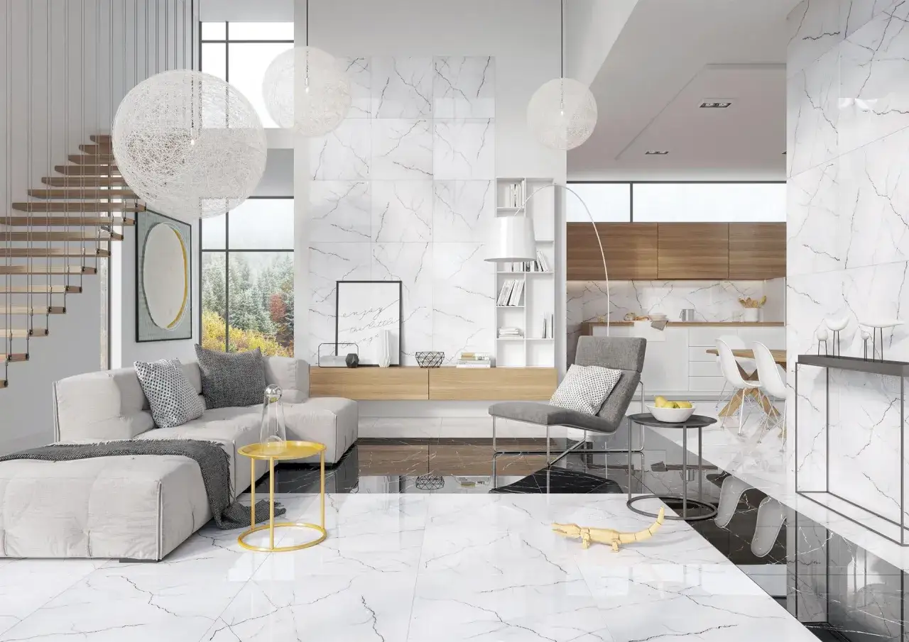 Nowoczesny salon z kuchnią, gdzie dominują płytki imitujące marmur biała marianna. Jasna przestrzeń, wygodna sofa, designerskie lampy i drewniane akcenty tworzą elegancką całość.