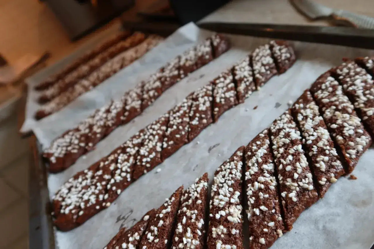 Chokladsnittar recept: M&ouml;rka, sockerstr&ouml;sslade kakor p&aring; bakpl&aring;tspapper, redo att gr&auml;ddas.