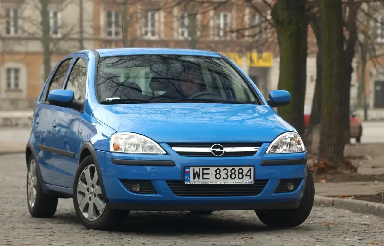 Niebieski Opel Corsa, idealny jako auta do 5 tys. zł. Zaparkowany na bruku, gotowy do jazdy.