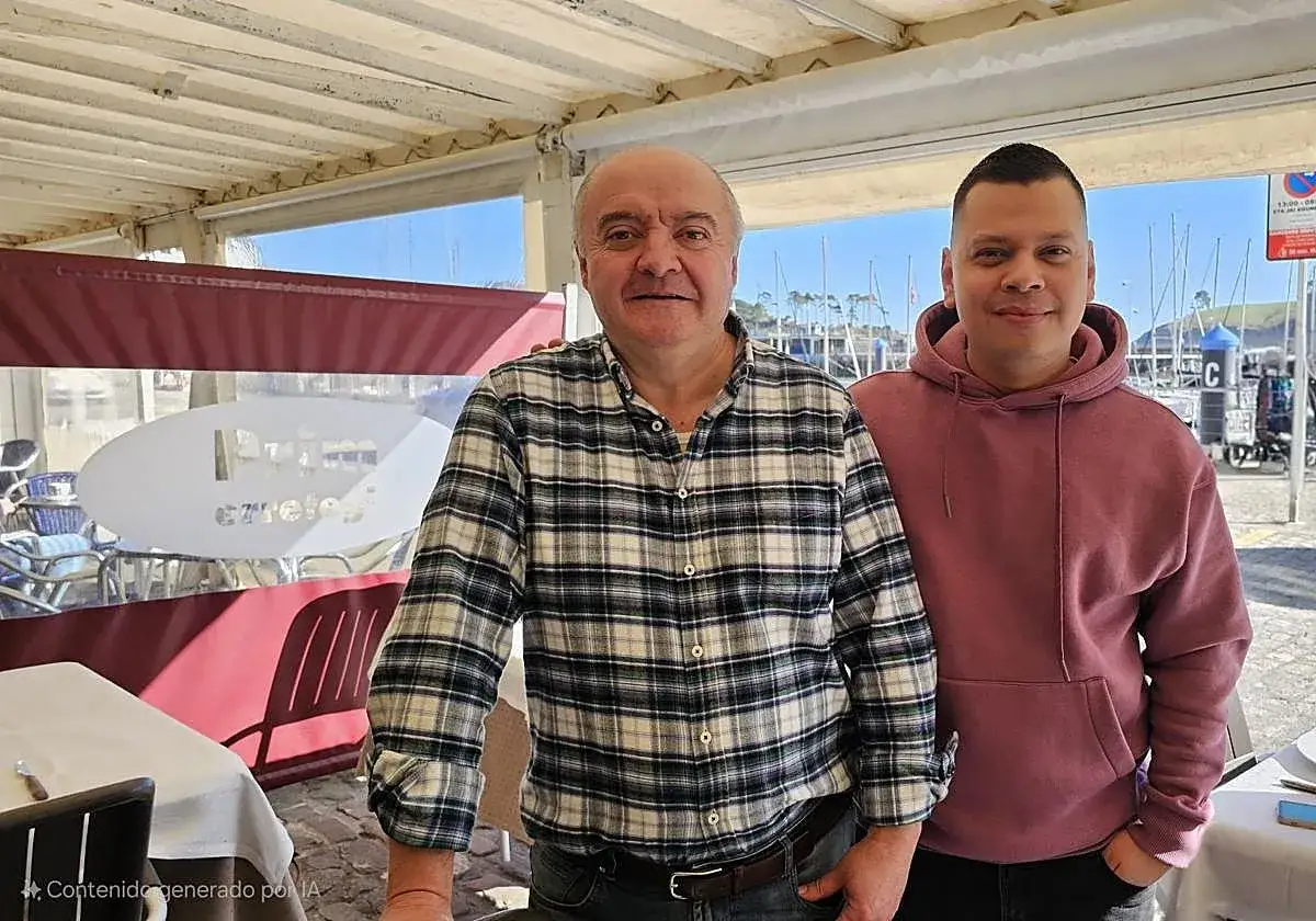 Dos hombres sonríen en un restaurante con vistas al puerto de Lekeitio. ¡Listos para comer!