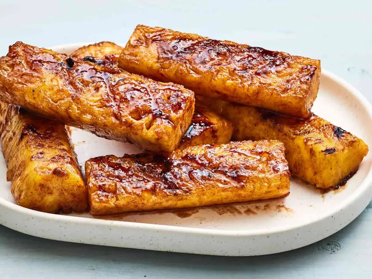 Trozo de piña a la plancha, caramelizada y dorada, servida en un plato blanco.