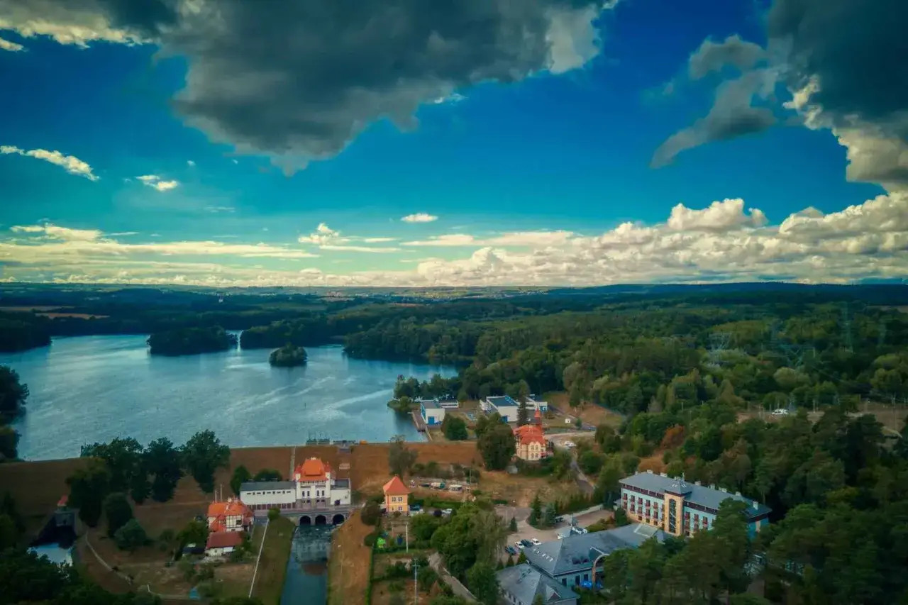 Malownicze jezioro i zabudowania nad tamą. Warto zobaczyć Kaszuby, to piękny region pełen zieleni i wody.