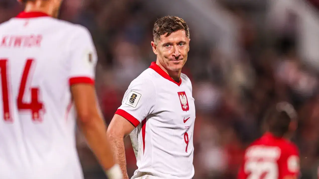 Robert Lewandowski w białej koszulce reprezentacji Polski, z numerem 9. Obok niego inny zawodnik kadry.