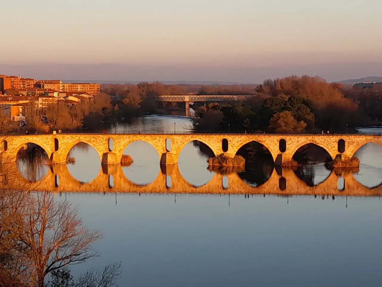 Puente de piedra con reflejo perfecto en el río Duero al atardecer. Merece la pena visitar Zamora por su belleza.