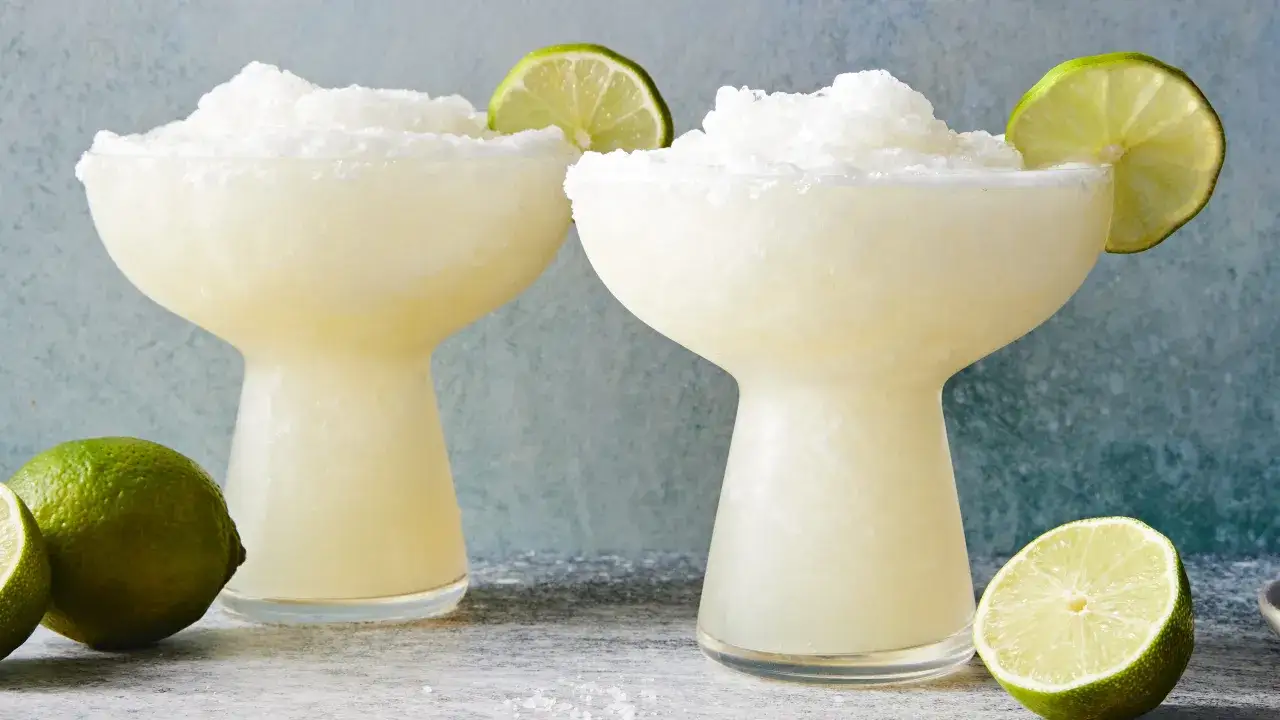 Två frostiga frozen margaritas med limeklyftor och saltkant. Perfekt för en varm sommardag.