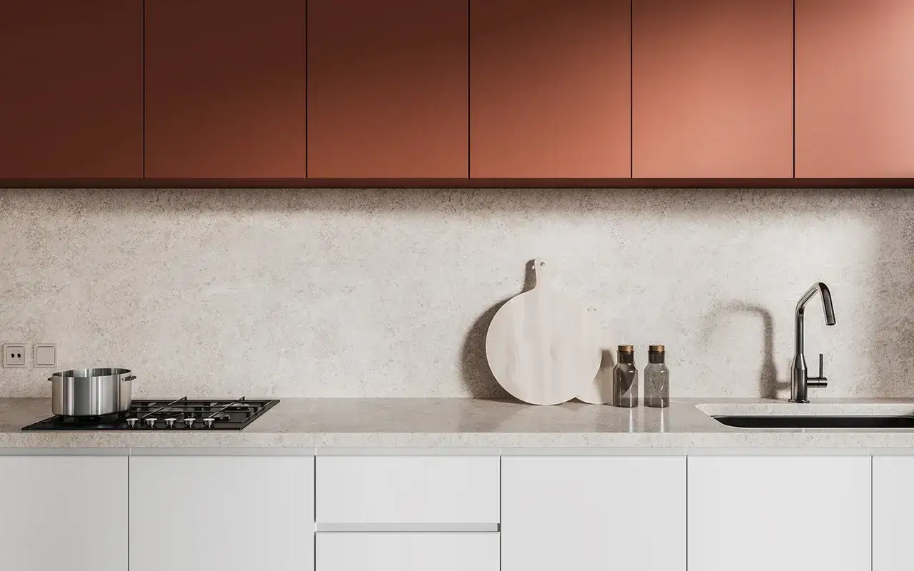 Cr&eacute;dence de cuisine moderne avec placards cuivr&eacute;s, plan de travail en marbre clair, plaque de cuisson, &eacute;vier et ustensiles.