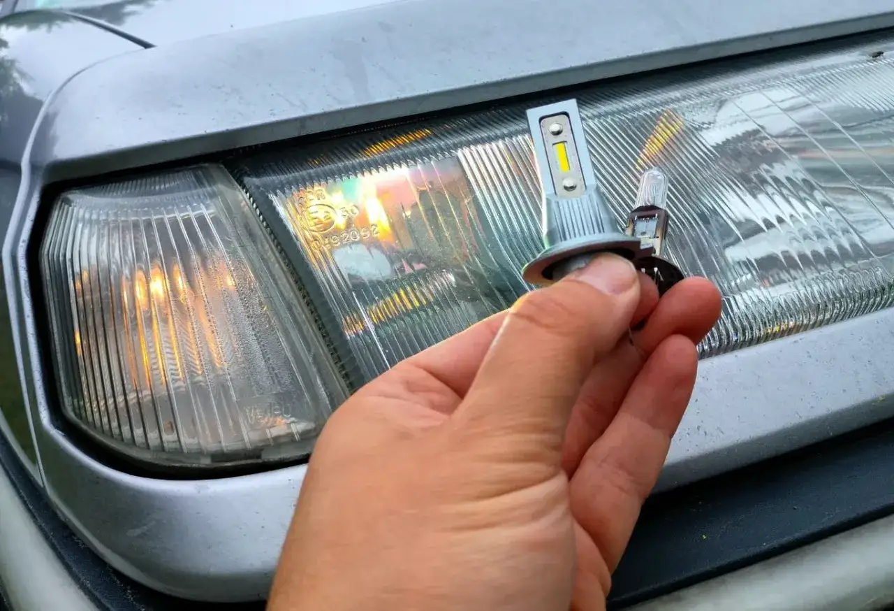 Dłoń trzyma żar&oacute;wkę LED do reflektora, por&oacute;wnując ją ze starą. Modernizacja oświetlenia to popularne retrofity w Polsce.