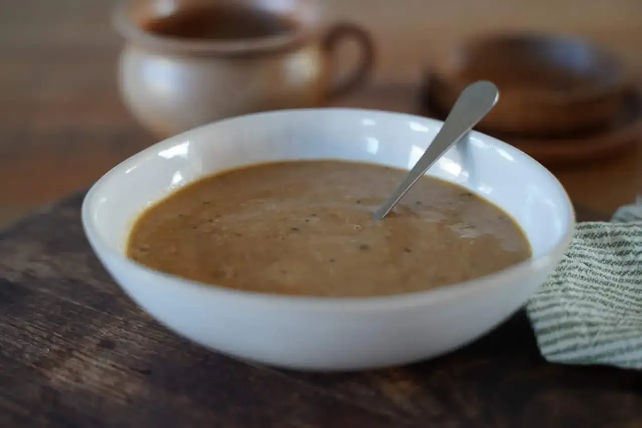 Un bol de sauce au poivre onctueuse, avec une cuillère en argent. Parfait pour accompagner un plat savoureux.