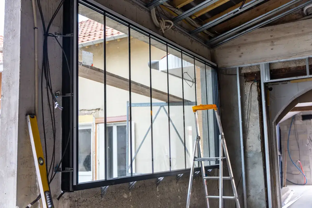 Instalaci&oacute;n de un gran ventanal como parte de un plan renove de ventanas. Se ve una escalera y herramientas de construcci&oacute;n.