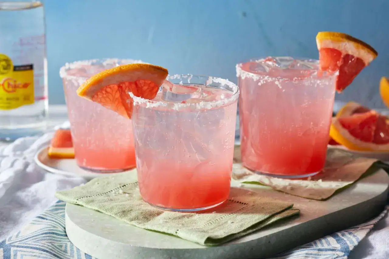 Tre glas med rosa drink, is och grapefruktklyfta. Saltkant p&aring; glasen.