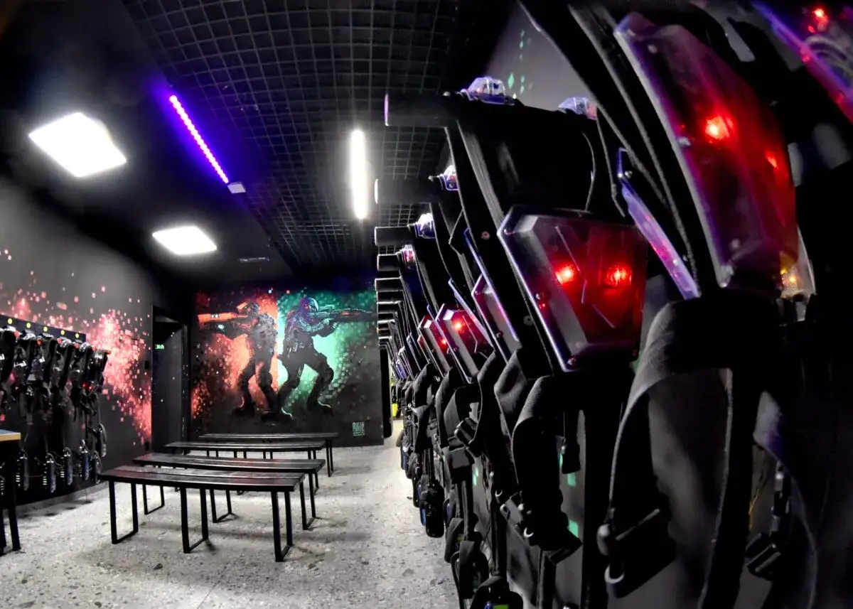 Gotowi na emocjonującą rozgrywkę w laser tag? Wygodne kamizelki czekają, a na ścianie mural z wojownikami zapowiada epicką bitwę.