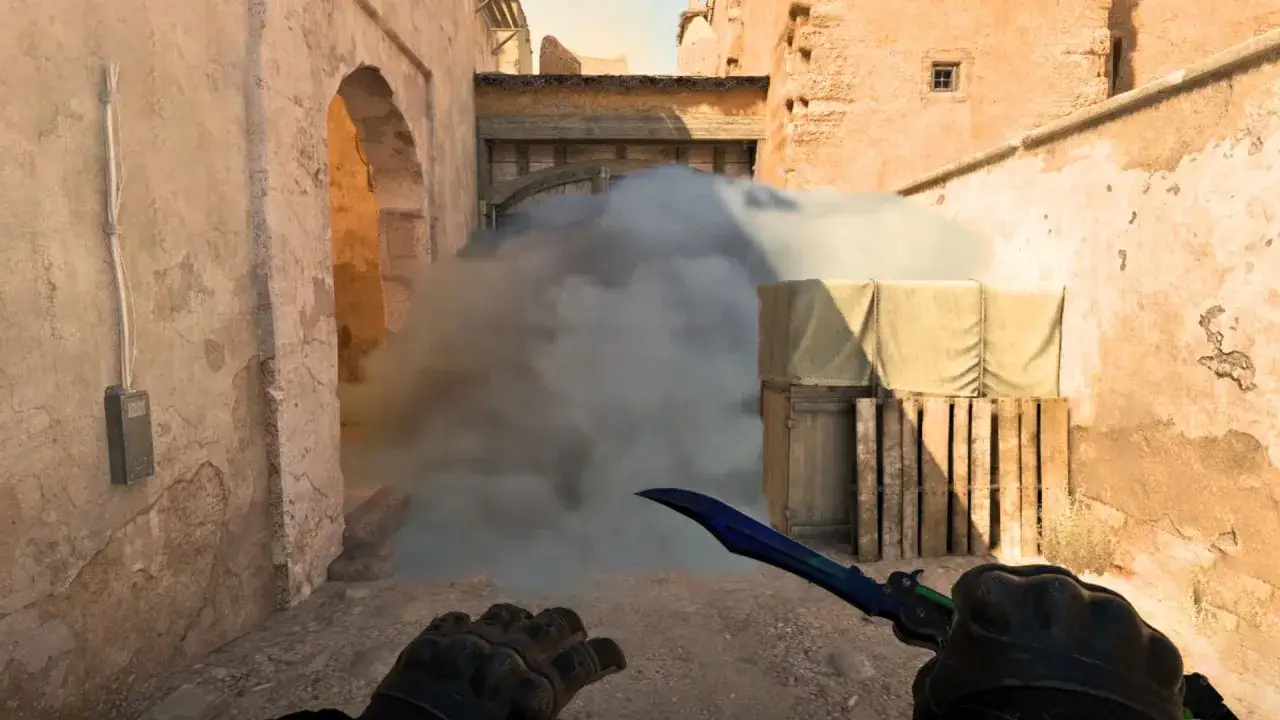 Ein Spieler im neuen Counter-Strike-Spiel wirft eine Rauchgranate in einer staubigen Gasse.