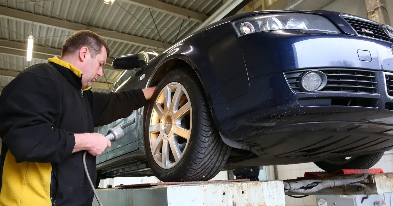 Mechanik sprawdza przyczynę, dla której auto gaśnie podczas jazdy. Podniesiony samochód na podnośniku.