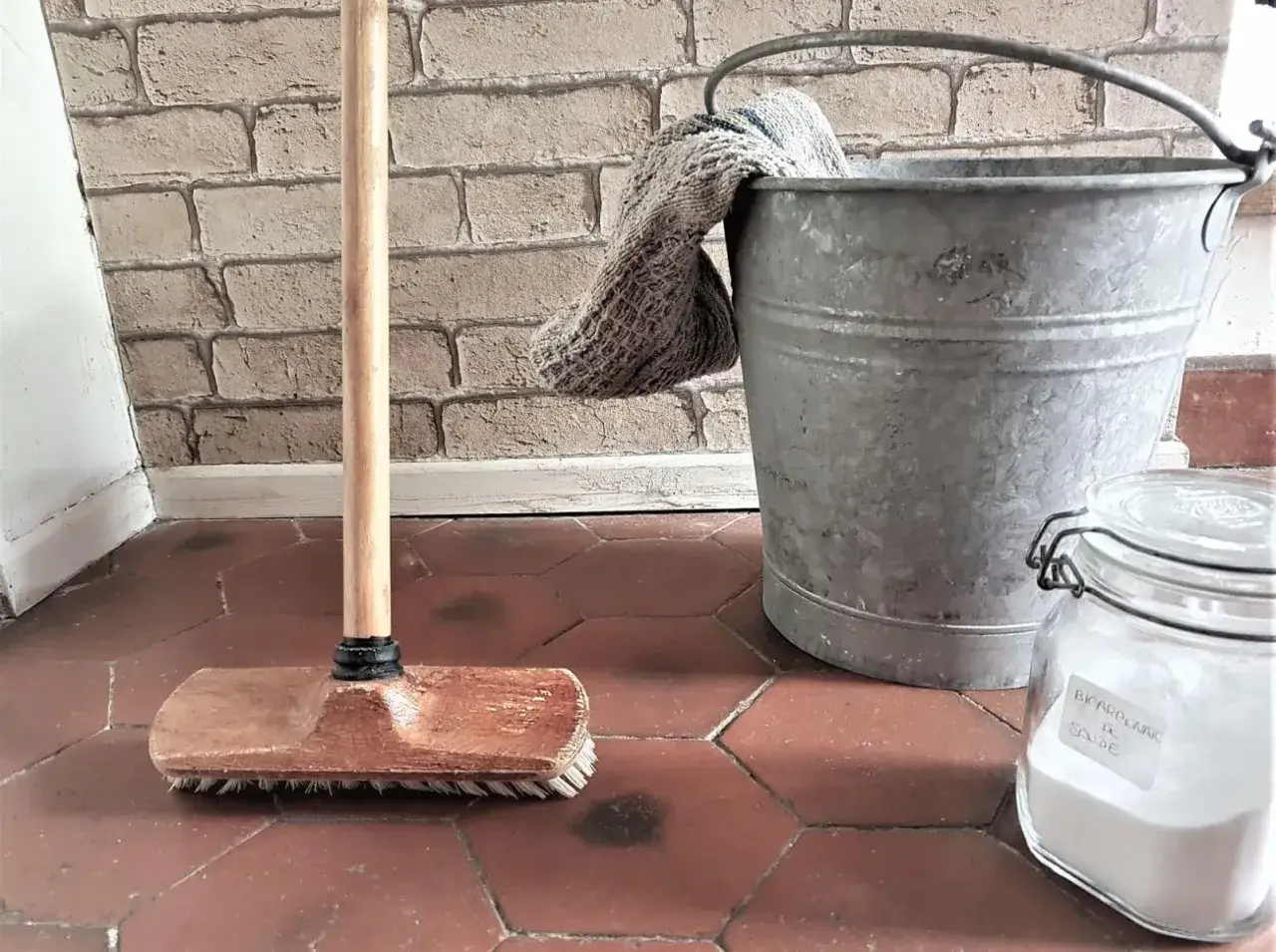 Balai, seau et bocal de bicarbonate de soude pr&ecirc;ts &agrave; nettoyer le sol sale.