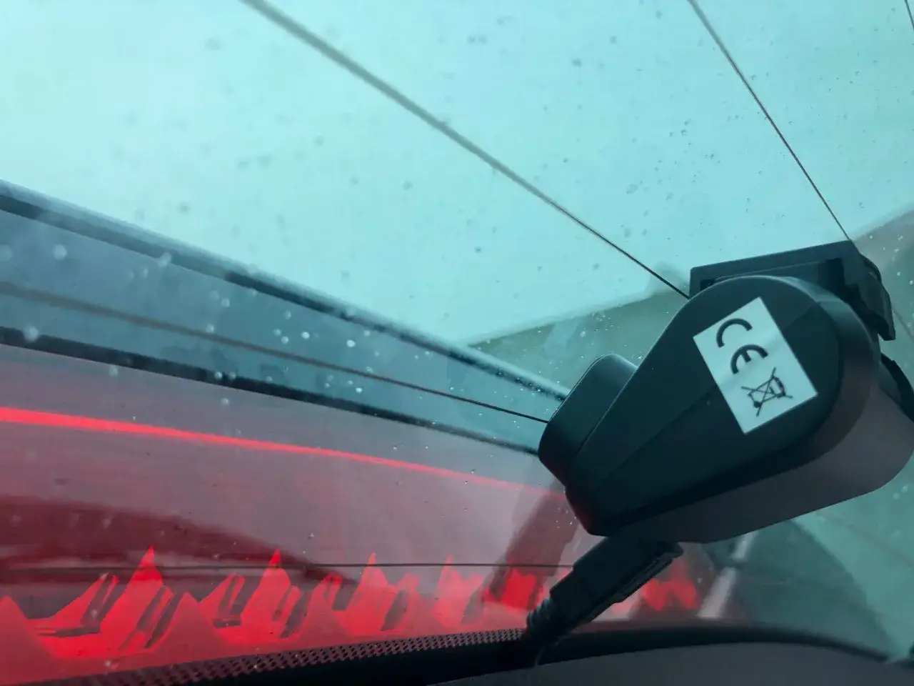 Kamera samochodowa z nalepką CE przyklejona do tylnej szyby. Dowiedz się, jak odkleić kamerę z szyby, gdy już nie jest potrzebna.
