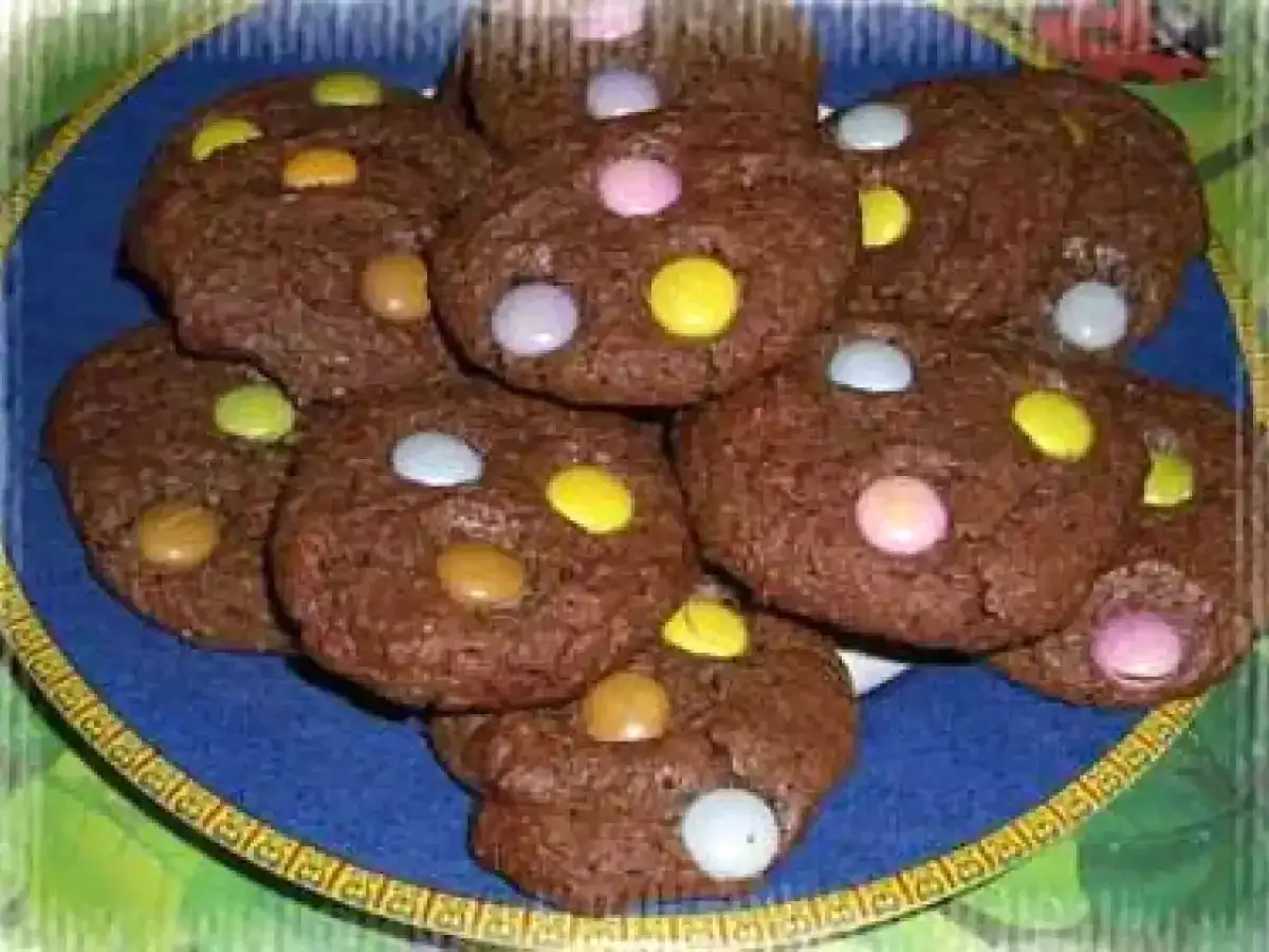 Gros plan sur une assiette bleue remplie de délicieux cookies chocolat smarties. Les couleurs vives des bonbons contrastent avec le chocolat noir.