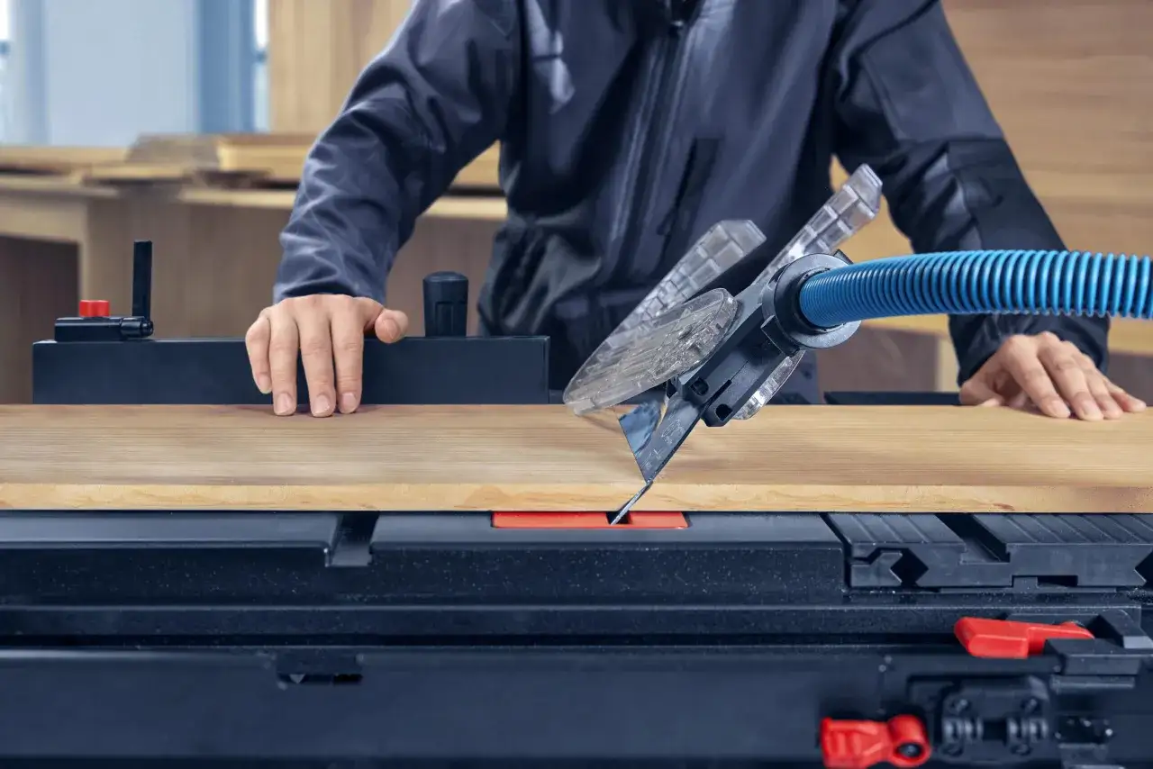 Menuisier travaillant le bois sur une scie circulaire, un outil de la marque Bosch.