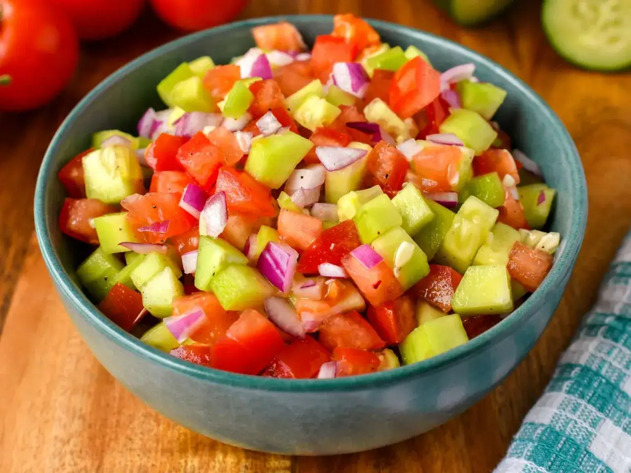 Frischer Tomaten-Gurken-Salat in einer Schüssel, garniert mit roten Zwiebeln. Perfekt für einen leichten Genuss.
