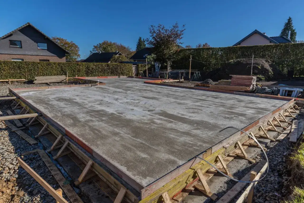 Frisch gegossene Bodenplatte mit Beton. Die hölzerne **Betonieren Schalung** ist noch sichtbar und stützt die Ränder.