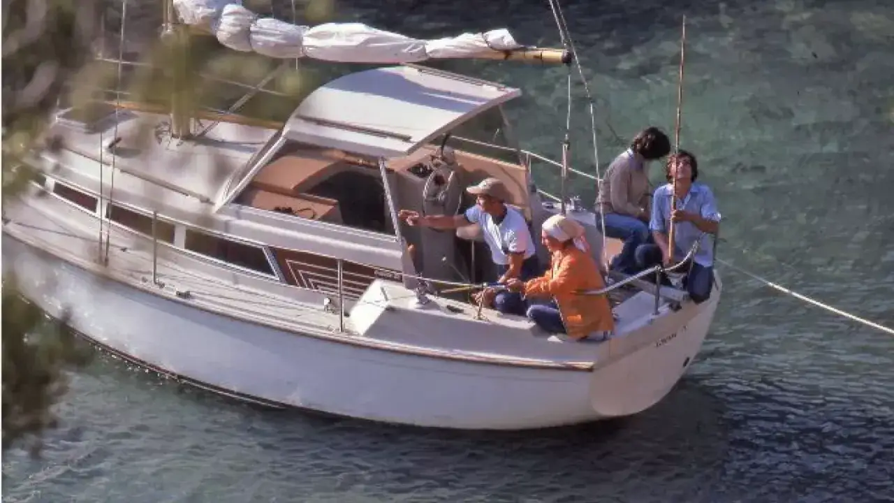 Quatre personnes sur un voilier blanc, l'Evasion 25, profitent d'une journée en mer. L'une d'elles pointe du doigt, peut-être en consultant la fiche technique.