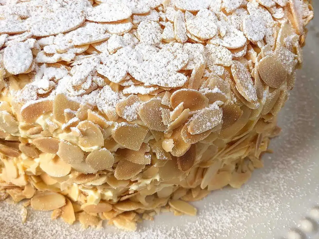 En närbild av en Oscar II tårta täckt med mandelspån och pudersocker.