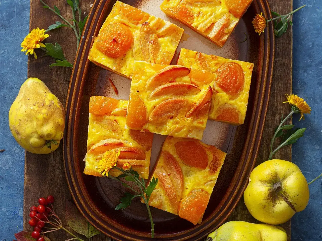 S&uuml;&szlig;er Kuchen mit Quittenfrucht-St&uuml;cken und ganzen Quitten daneben.