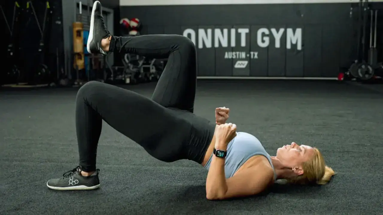 Kobieta wykonuje ćwiczenie na pośladki, unosząc biodra z jedną nogą w górze. Świetna alternatywa co zamiast hip thrust.