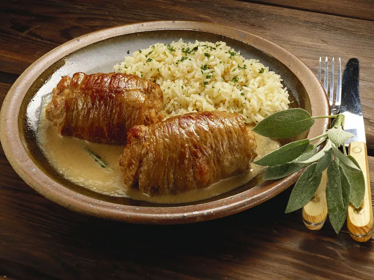 Deux paupiettes de veau en sauce crémeuse, accompagnées de riz et de feuilles de sauge. Quel vin avec des paupiettes de veau ? Un blanc corsé ou un rouge léger.