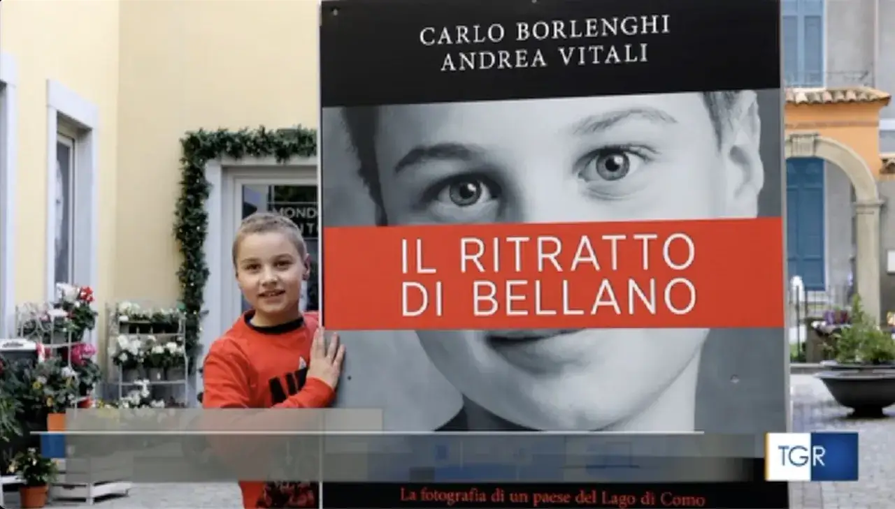 Un bambino sorride accanto a un cartellone che promuove 