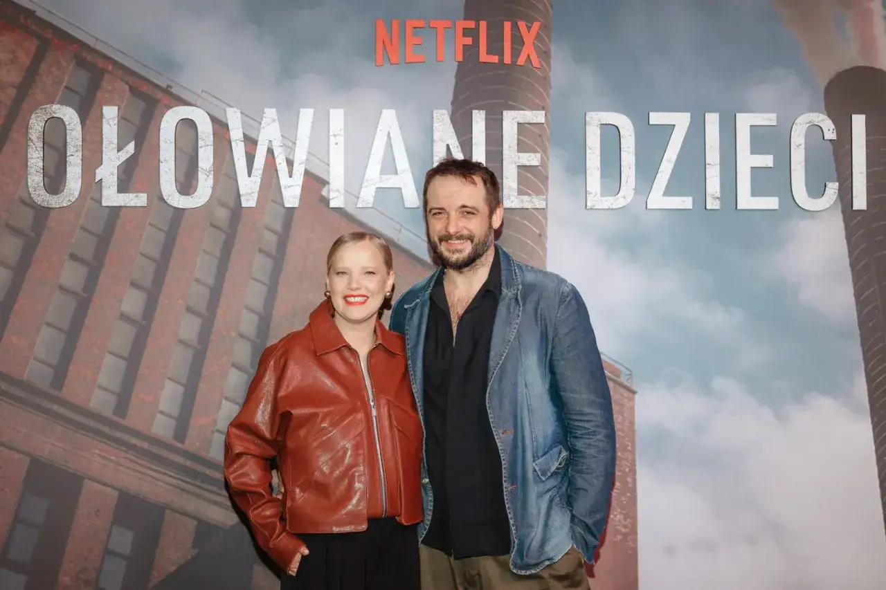Hubert Niedziela z uśmiechem pozuje obok aktorki na tle plakatu 