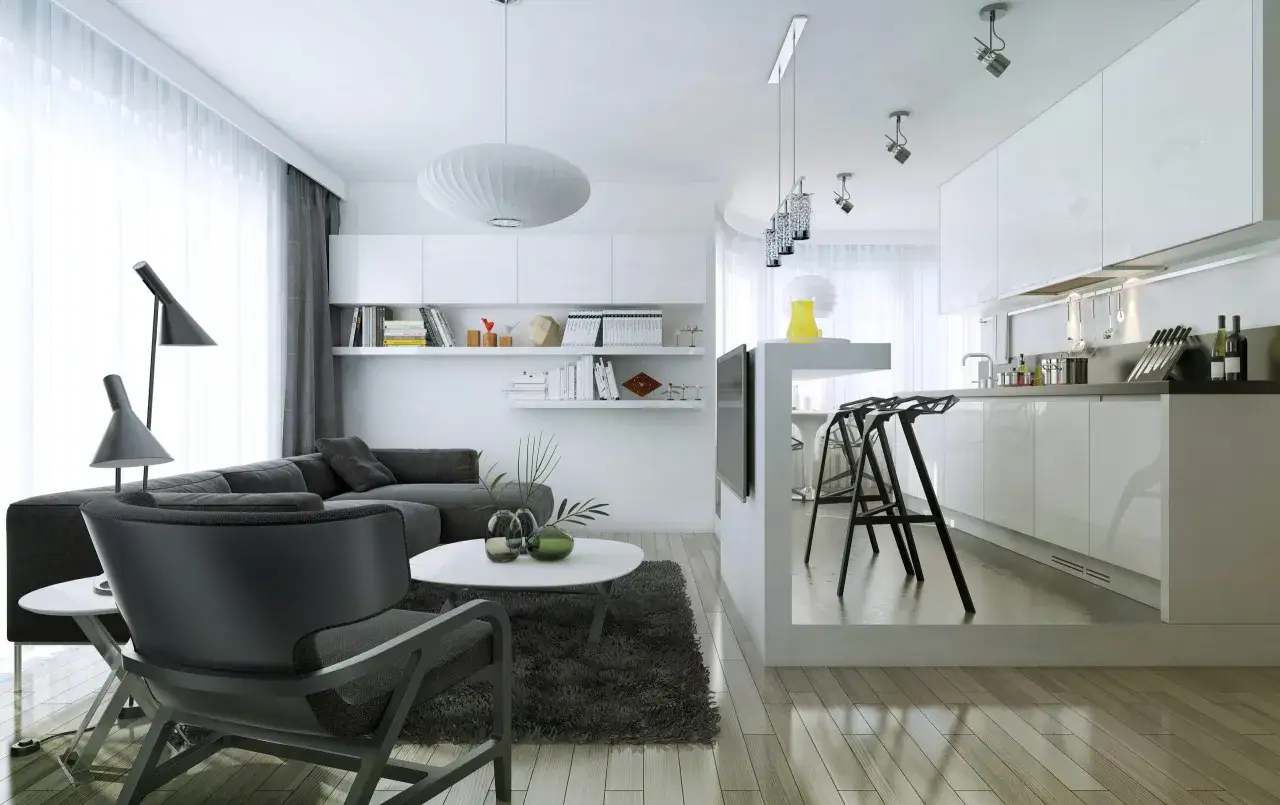 Salon moderne avec canapé gris, table basse et une petite cuisine ouverte blanche et épurée.